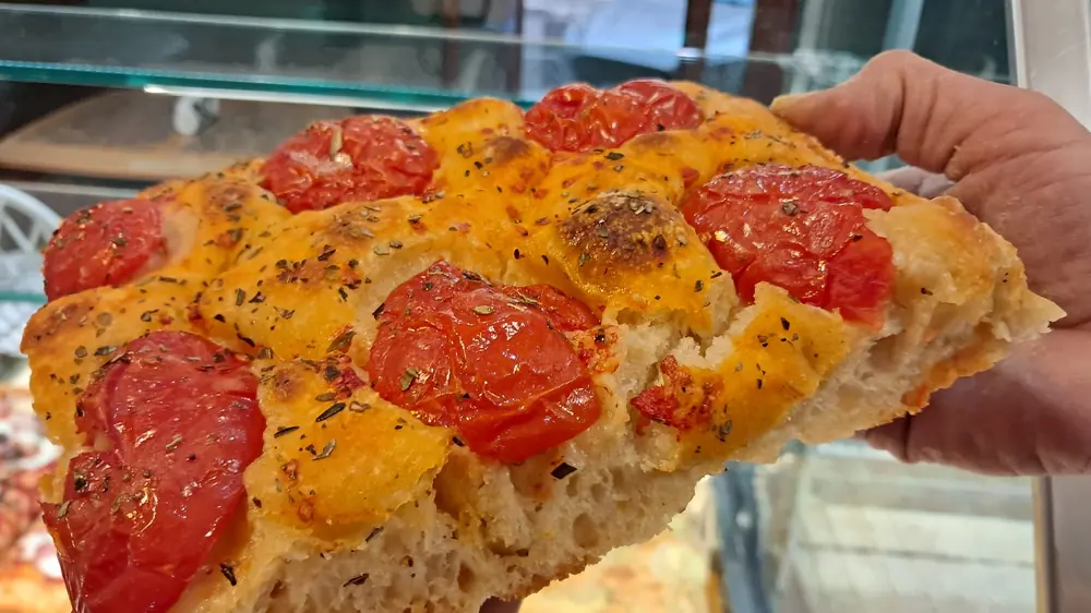 Un trancio di focaccia con i pomodorini, appena tagliato