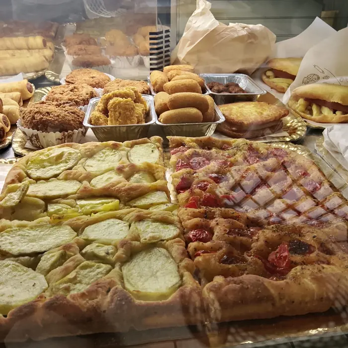 La focaccia alle patate e quella con pomodorini e pancetta, con i rustici sul ripiano alto