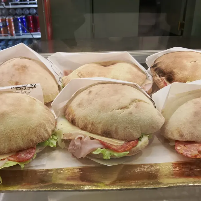 Pucce farcite con prosciutto, salame e insalata, incartate sul vassoio