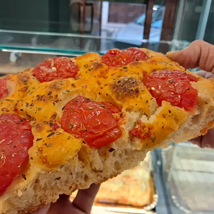 Un trancio di focaccia con pomodorini e origano, appena tagliato